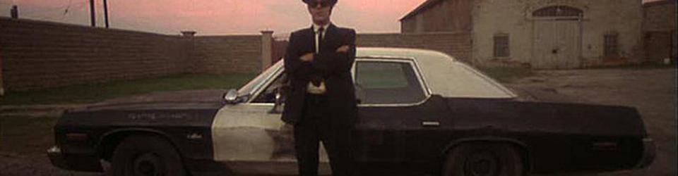 Cover À écouter avec un chapeau noir et des lunettes noires dans une ancienne voiture de flics sur les routes de l'illinois